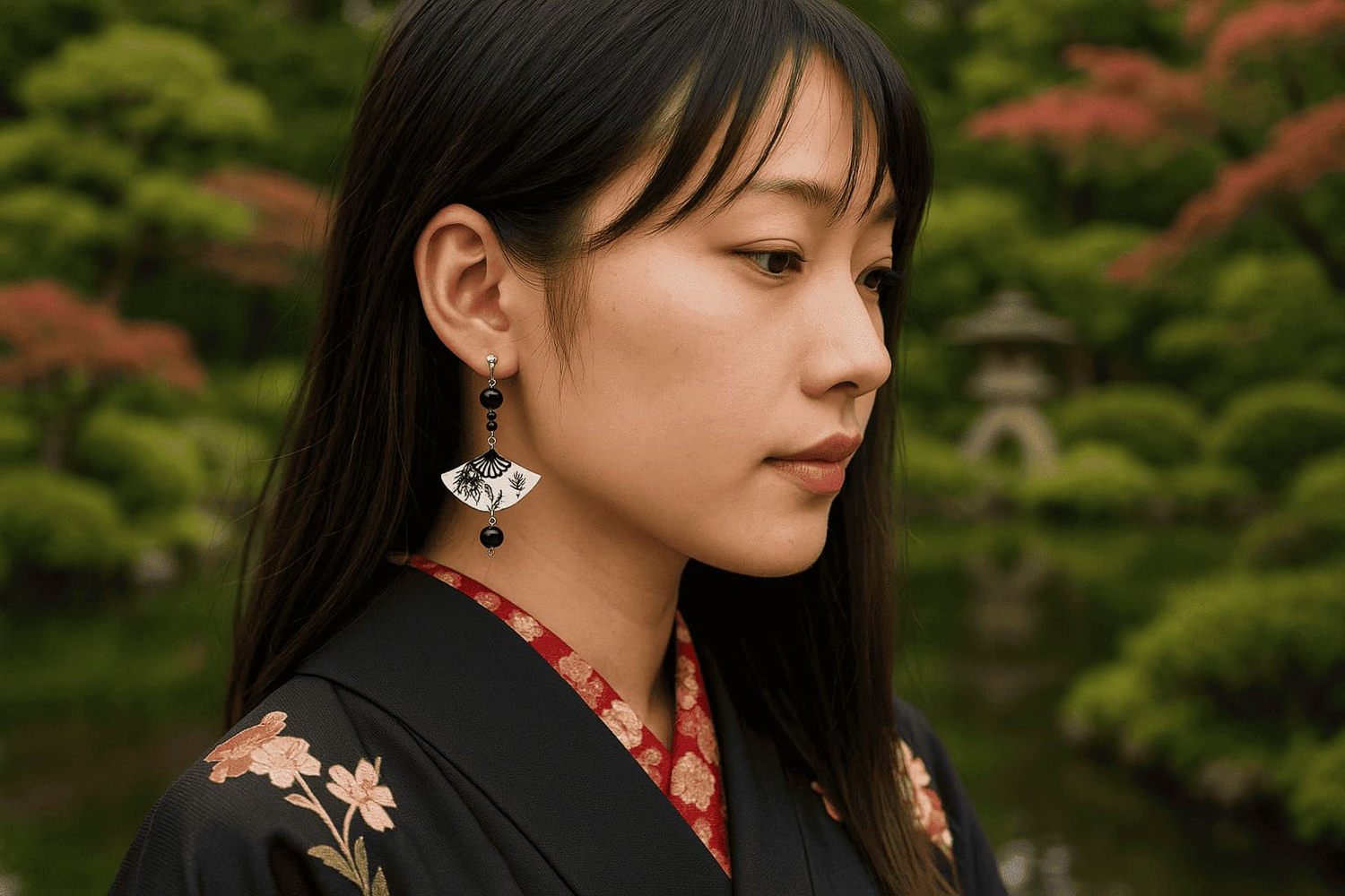 femme en kimono noir portant une boucle d’oreille japonaise noire et argent en forme d’éventail, dans un jardin traditionnel