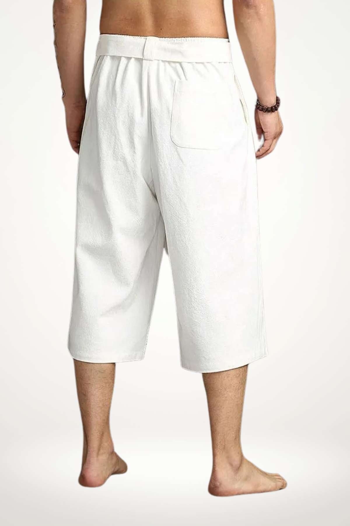 Pantalon kimono blanc, coupe ample, matière douce, porté par un homme debout, décor minimaliste en arrière-plan