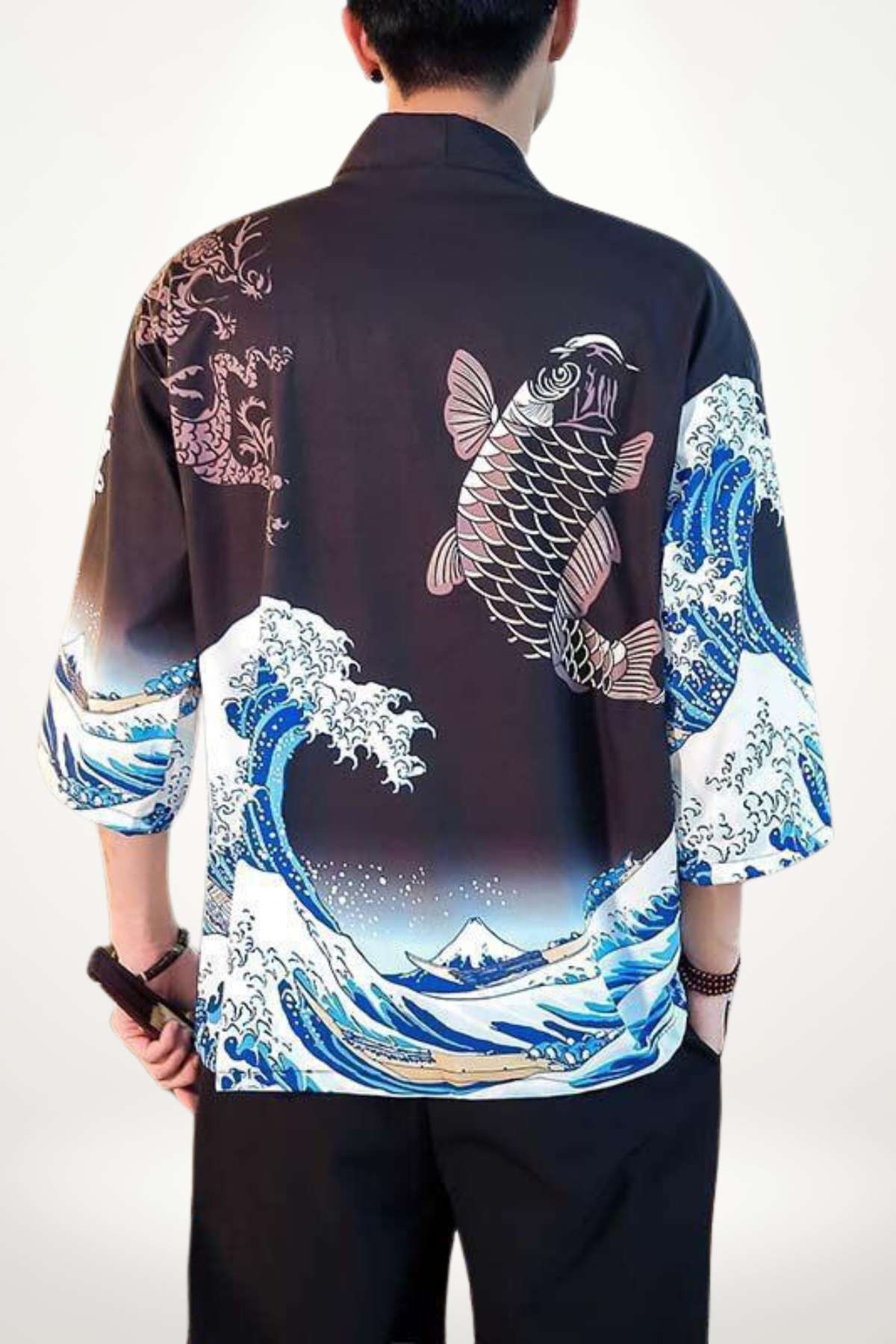 Un kimono japonais noir avec des motifs de vagues bleues et de poissons sur les manches, porté par un homme