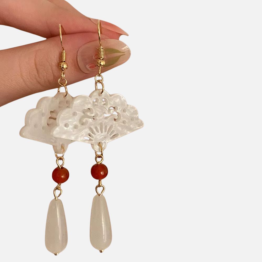 Boucles d'oreilles en forme d'éventail, ornées de perles rouge et blanche, suspendues par des crochets dorés, évoquant un style japonais.