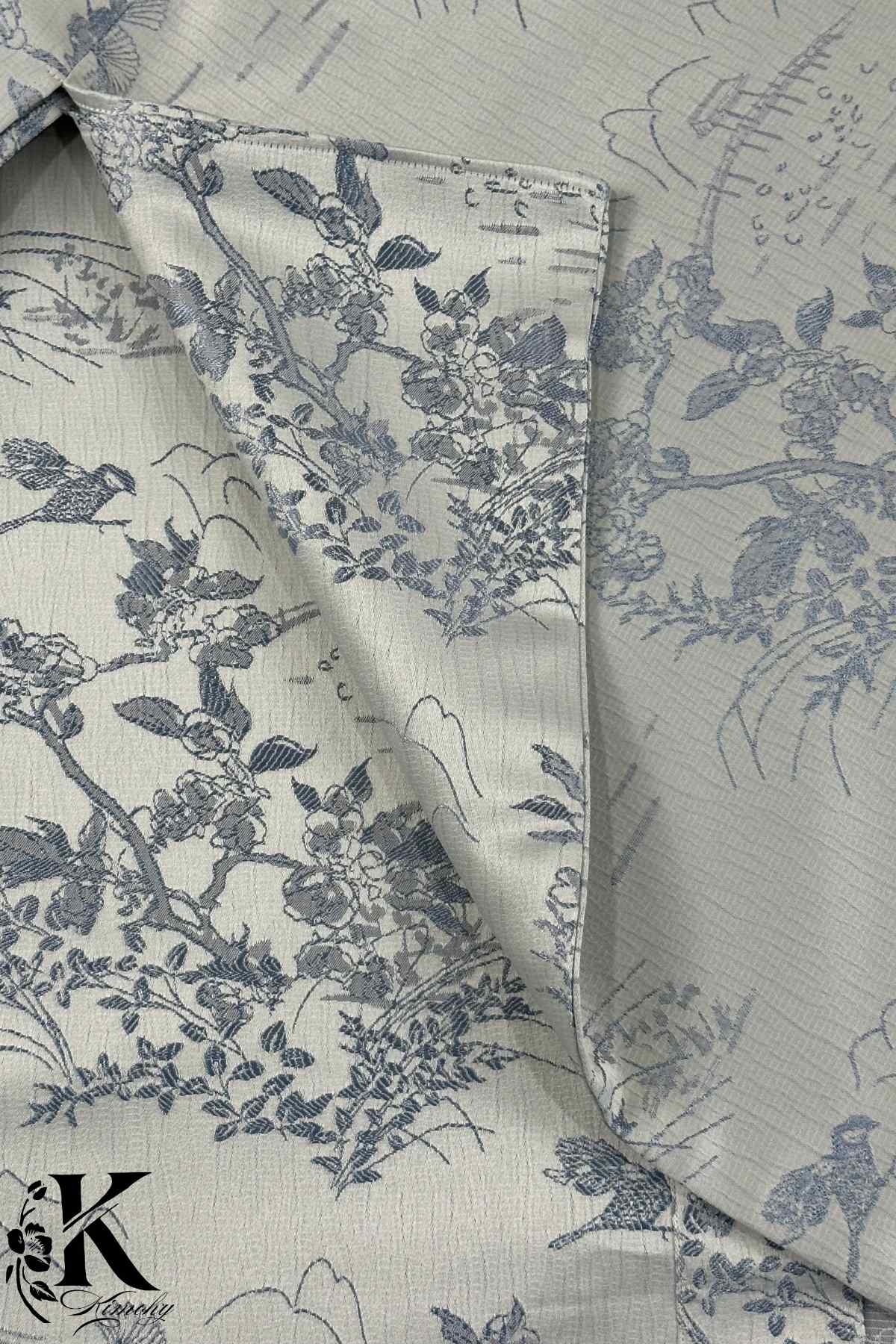 Tissu de kimono gris clair avec motifs floraux et oiseaux en bleu, texture légèrement plissée et élégante