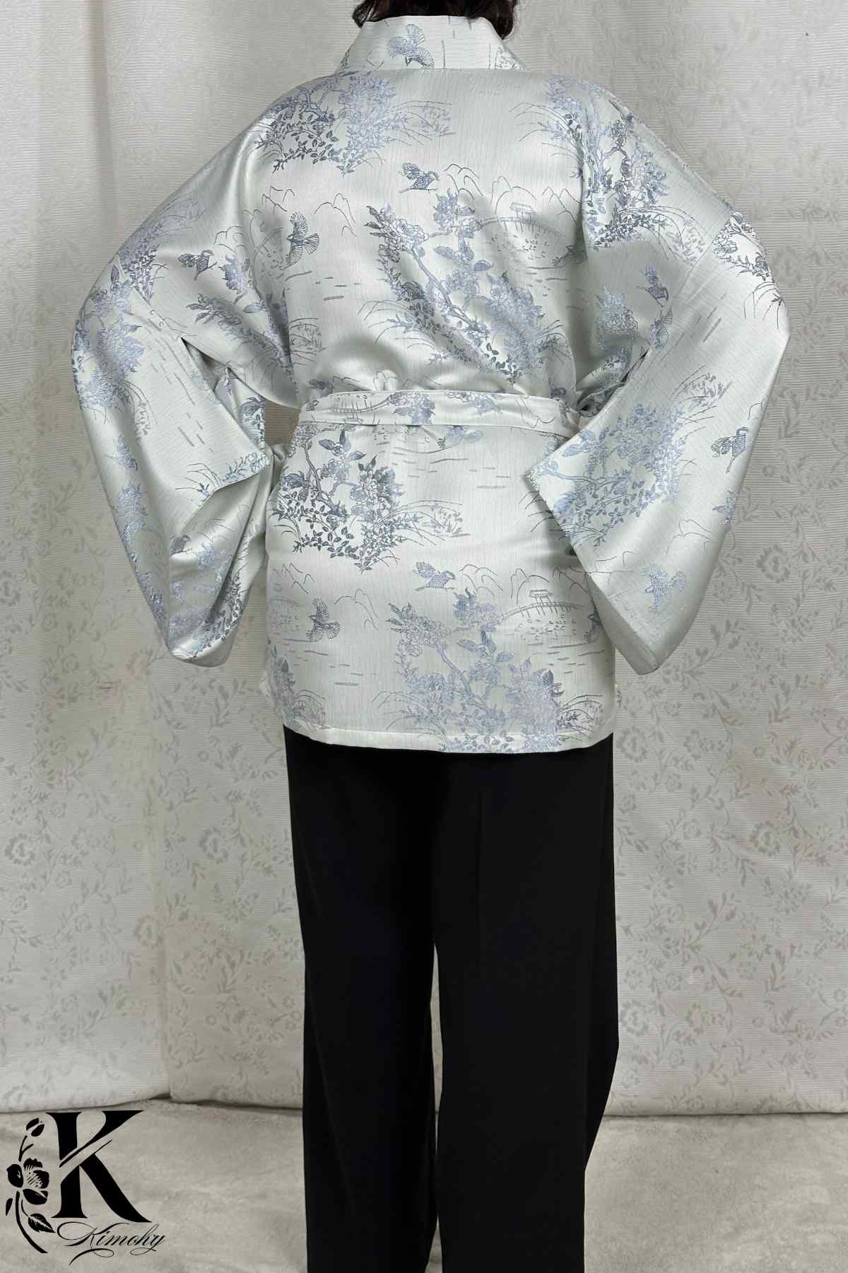 Kimono en satin argenté avec motifs floraux bleus, porté avec un pantalon noir dans un décor sobre