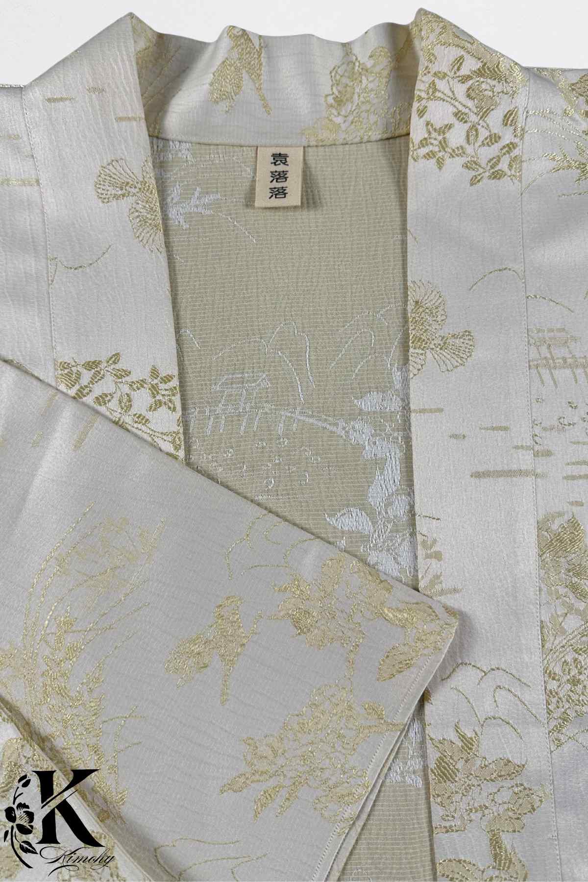 Kimono en soie blanche avec motifs floraux dorés sur fond beige, élégant et raffiné, évoquant le style japonais