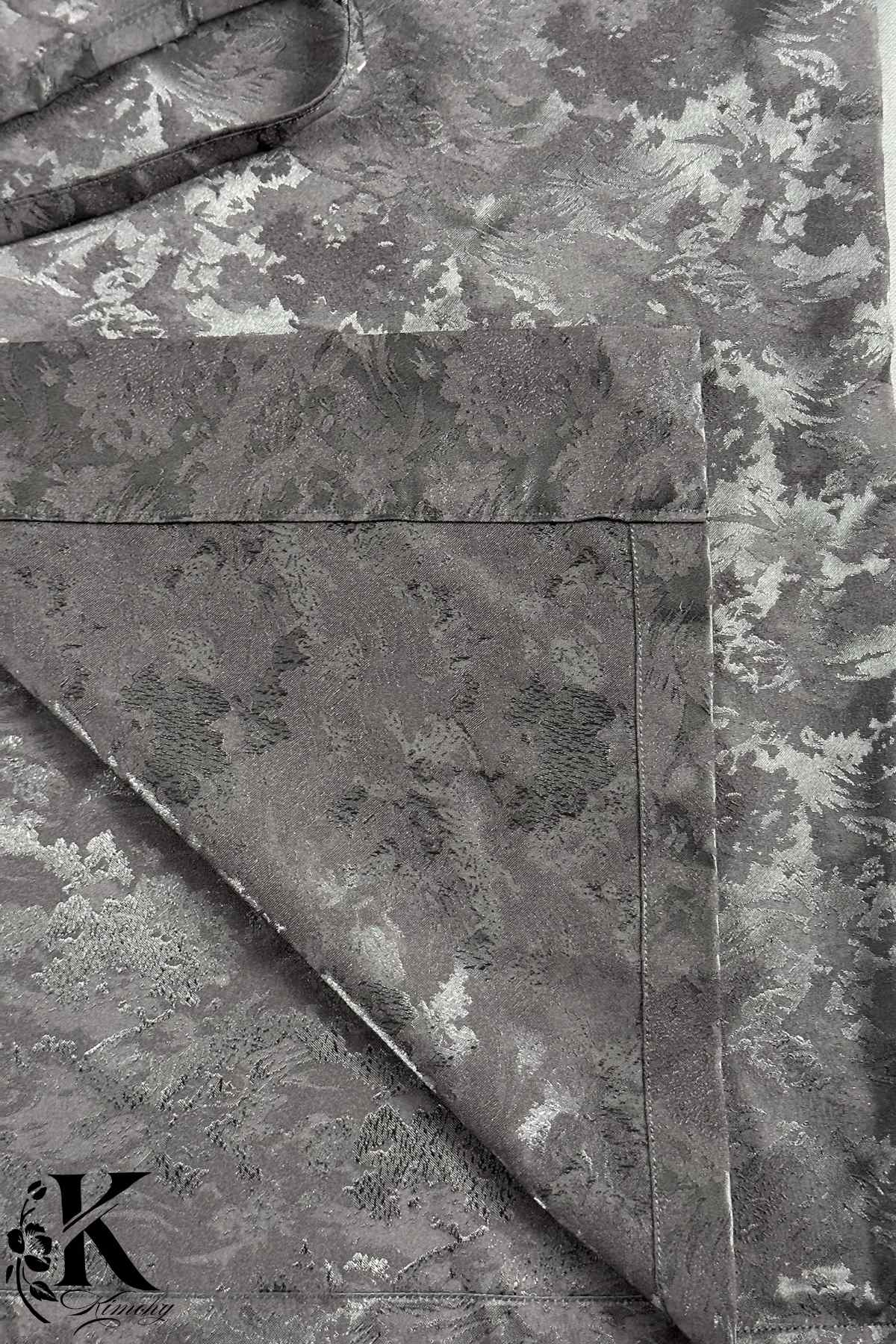 Kimono en tissu gris avec motifs floraux argentés, drapé élégamment sur un fond neutre