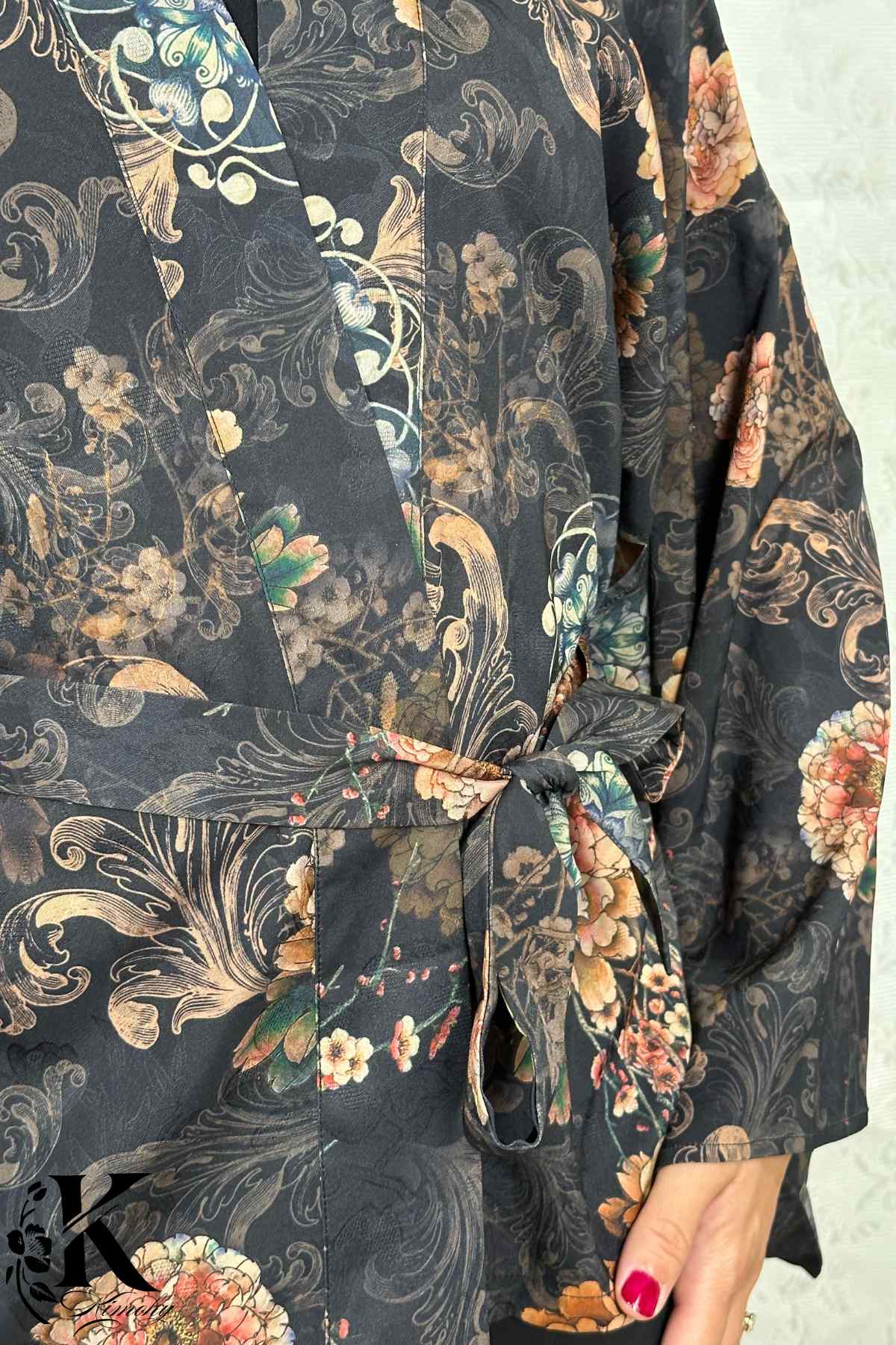 Kimono noir à motifs floraux colorés, ceinturé à la taille, porté dans un jardin obscur