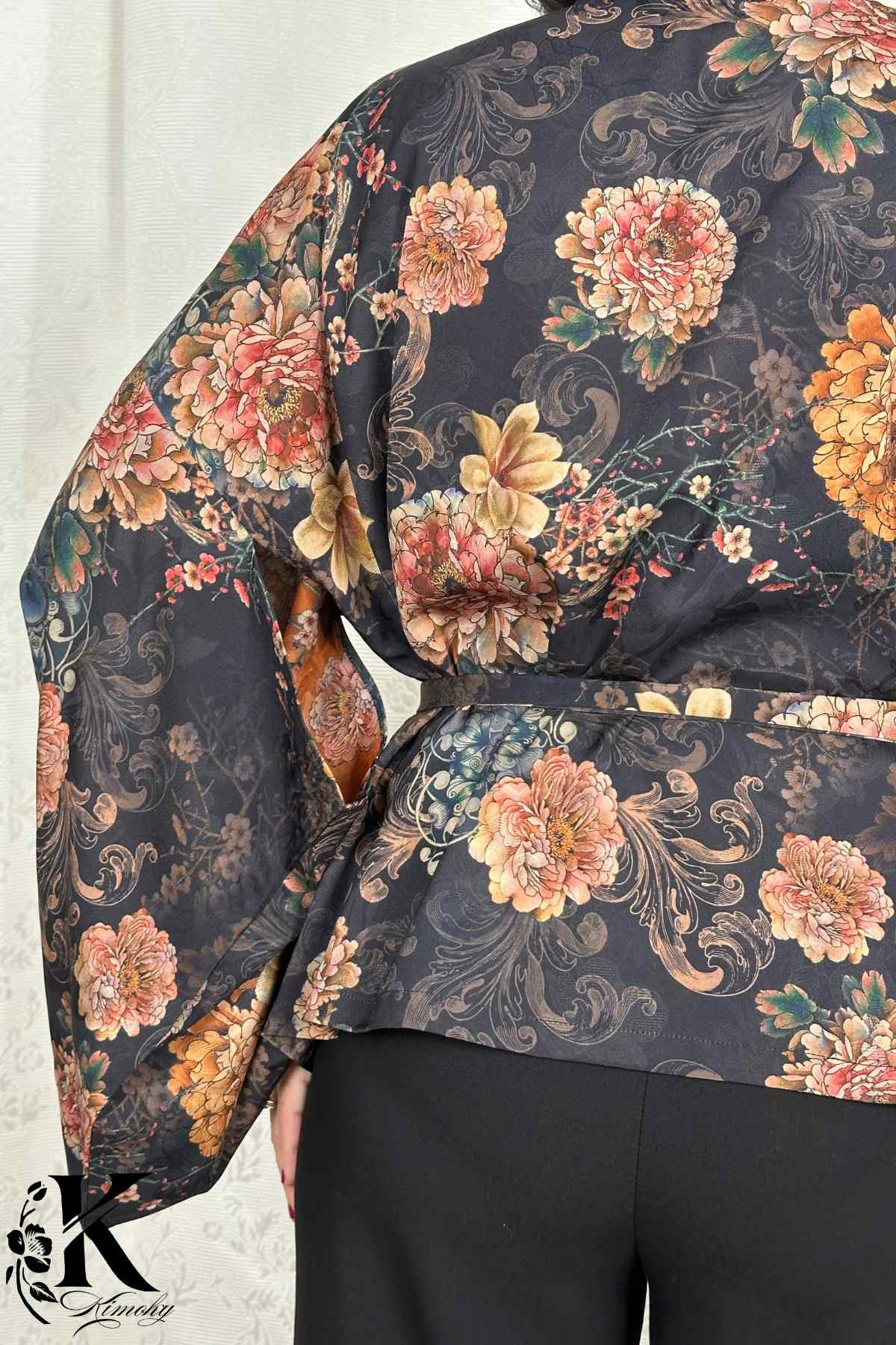 Kimono noir à fleurs colorées, manches larges, porté dans un décor de jardin obscur, style japonais élégant