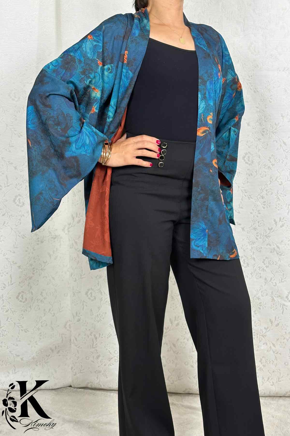 Femme portant un kimono bleu et orange avec motifs floraux, dans un décor sobre et élégant