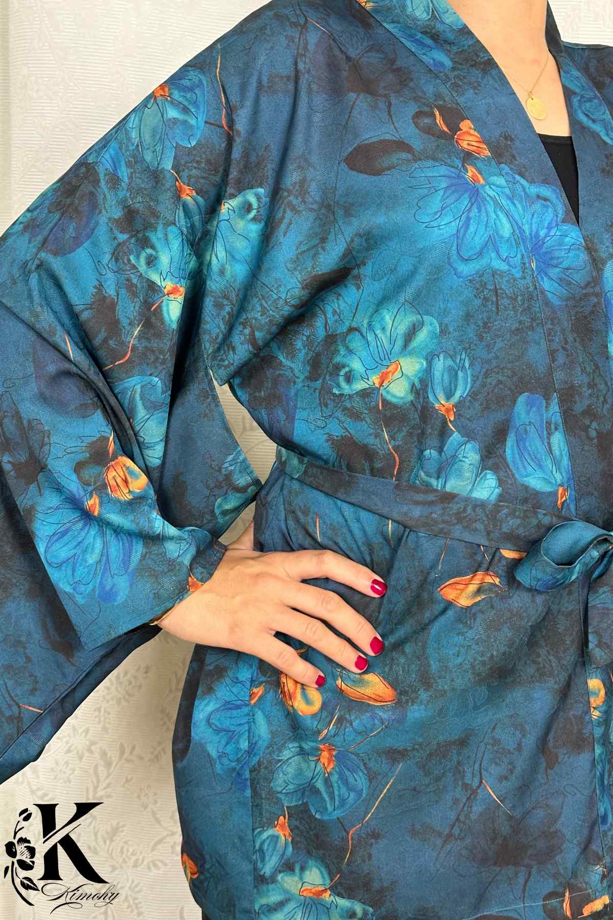 Kimono en tissu bleu avec motifs floraux, manches larges, porté avec une ceinture, dans un décor sobre