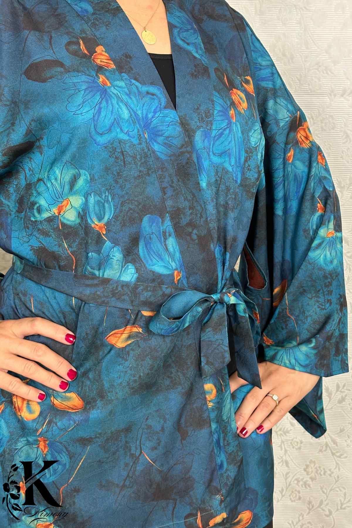 Kimono en tissu bleu avec motifs floraux orange, porté par une femme dans un décor sobre et élégant