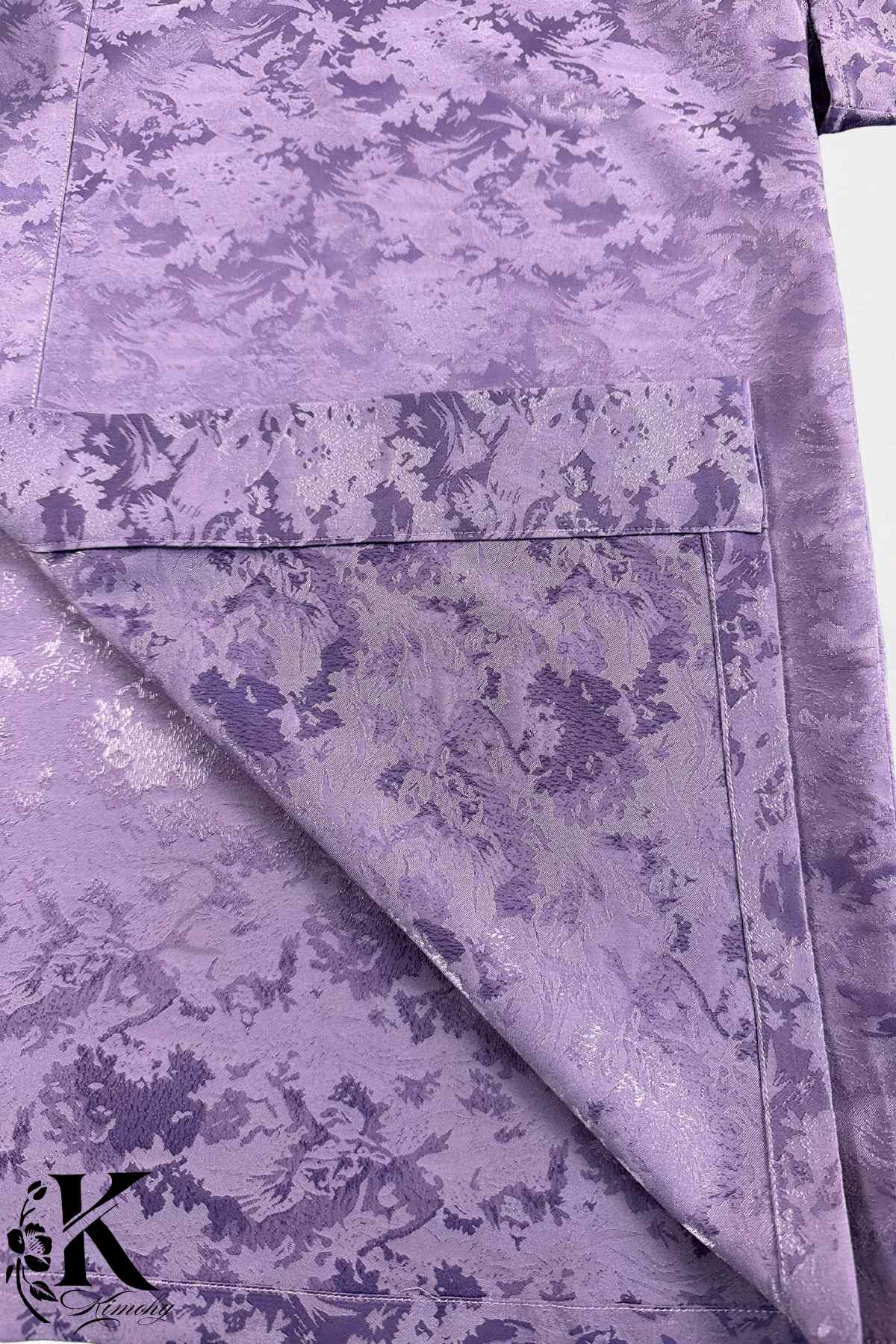 Veste kimono en satin violet avec motifs floraux subtils, présentant une texture lisse et élégante