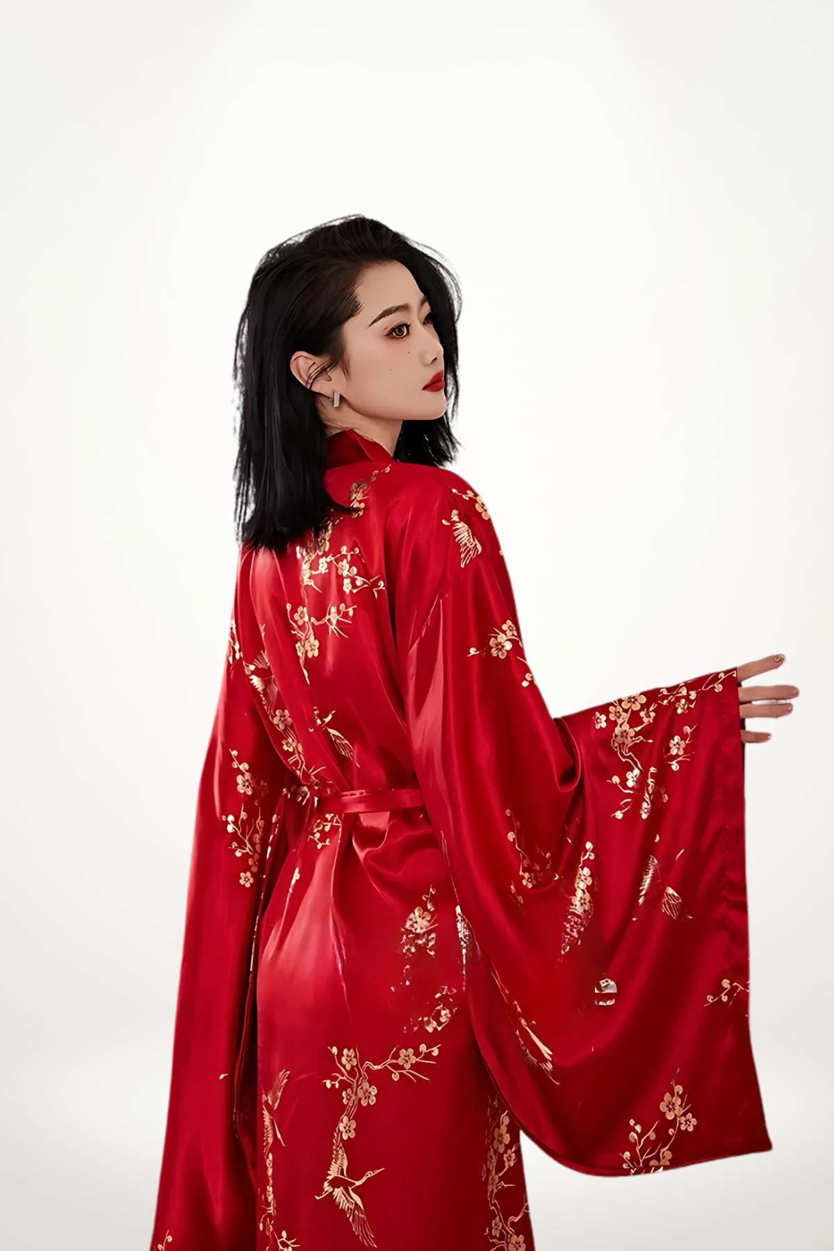 Kimono long en satin rouge avec motifs dorés, porté par une femme aux cheveux noirs, dans un décor minimaliste