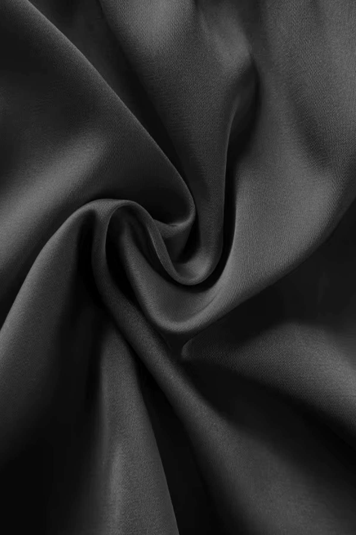 Tissu noir satiné enroulé, présentant une texture lisse et brillante, évoquant l'élégance d'un kimono