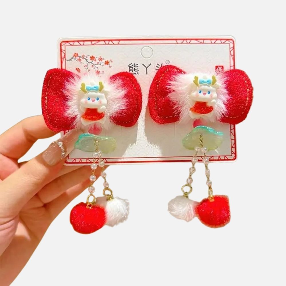 Barrette en forme de nœud rouge avec des pompons blancs et un motif kawaii au centre