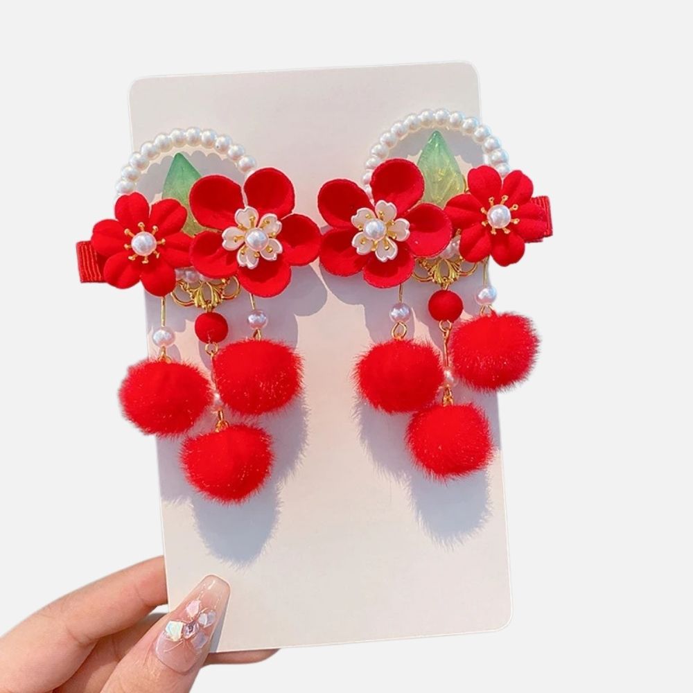 Bijou de cheveux rouge avec fleurs, perles blanches et pompons en fourrure, sur fond neutre