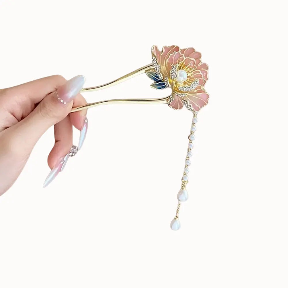 Épingle métallique dorée surmontée d’une fleur.