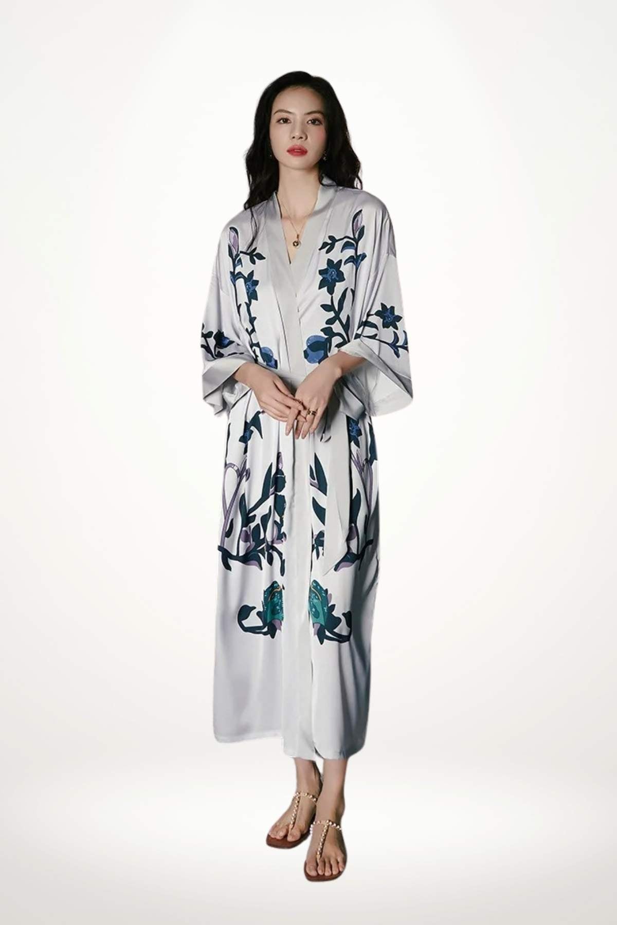 Kimono blanc orné de motifs floraux bleus, porté par une femme aux cheveux longs, fond neutre