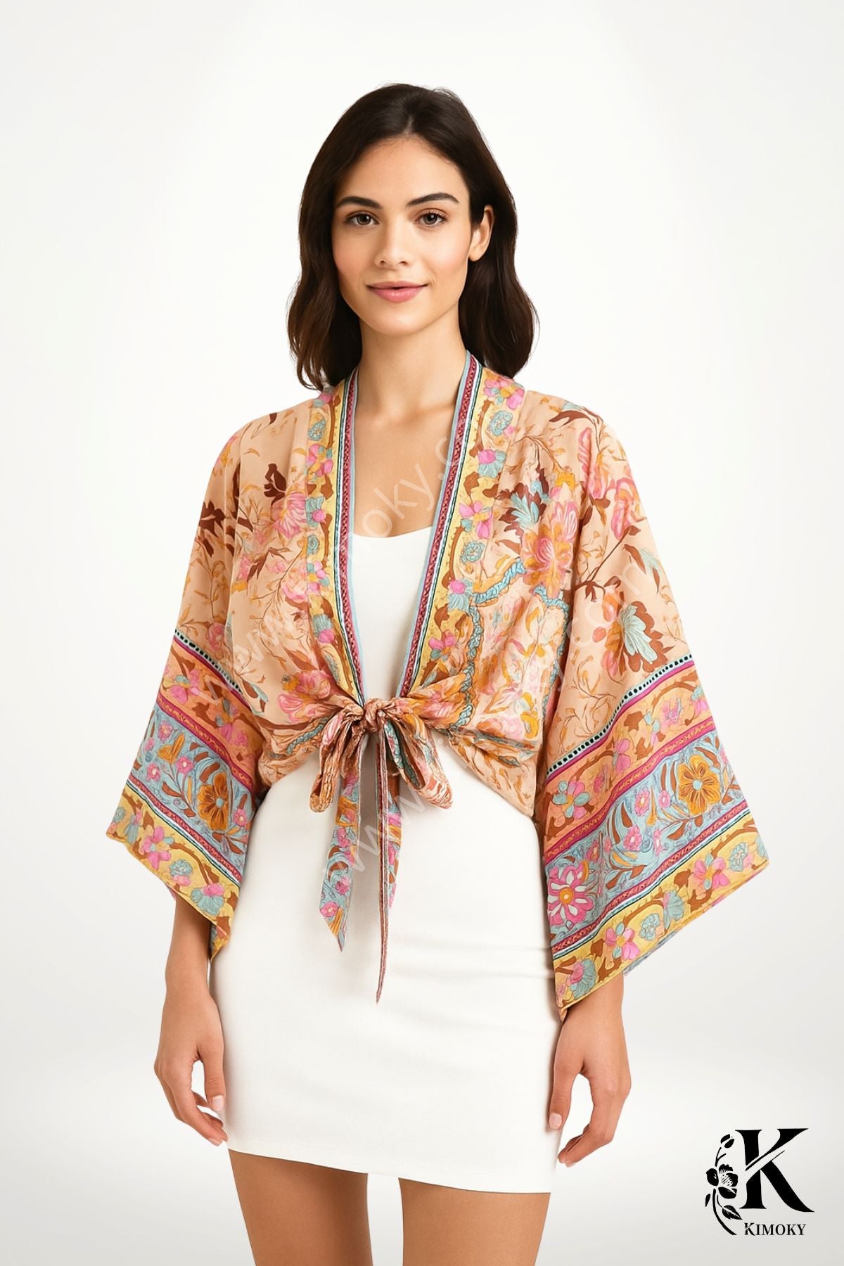 Femme en robe blanche portant un kimono femme court en coton beige à fleurs multicolores rose orange turquoise, style bohème chic pour l’été