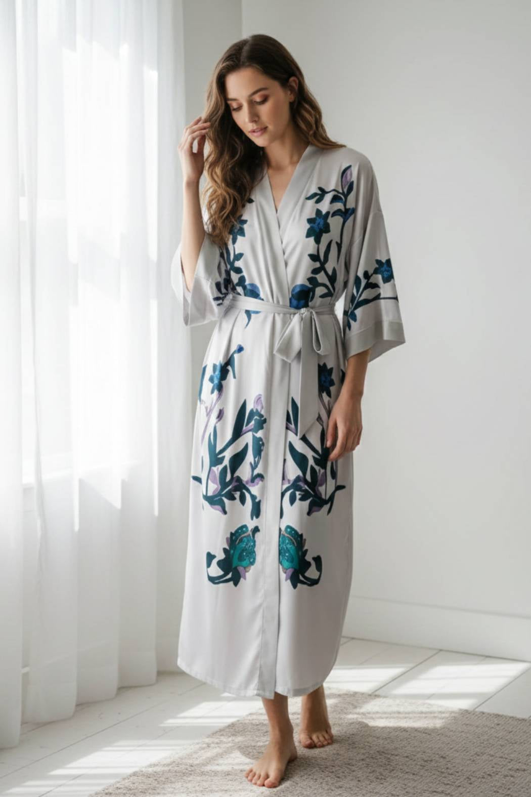Une femme porte un kimono gris orné de fleurs bleues et violettes, dans un décor lumineux et épuré