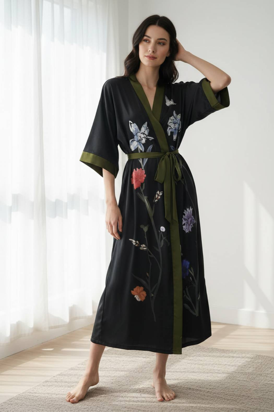 Kimono noir élégant avec des motifs floraux colorés et une ceinture verte, porté par une femme debout dans un intérieur
