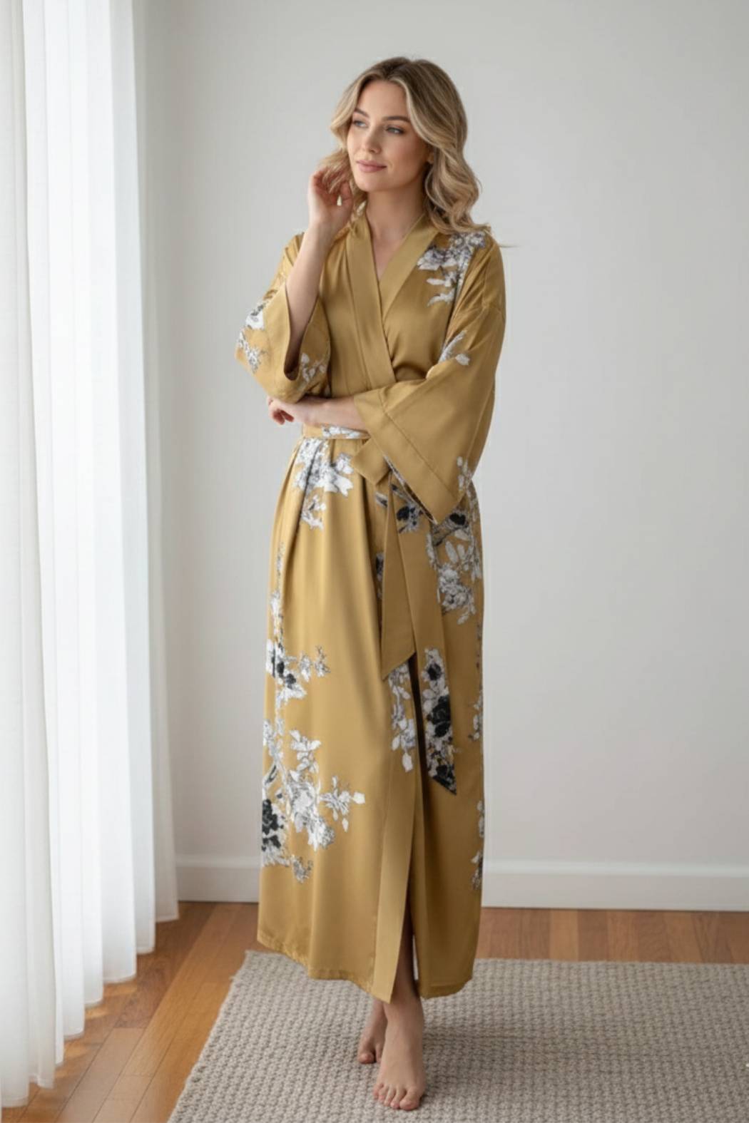 Femme en kimono satin doré avec motifs floraux, posant dans un décor minimaliste et lumineux