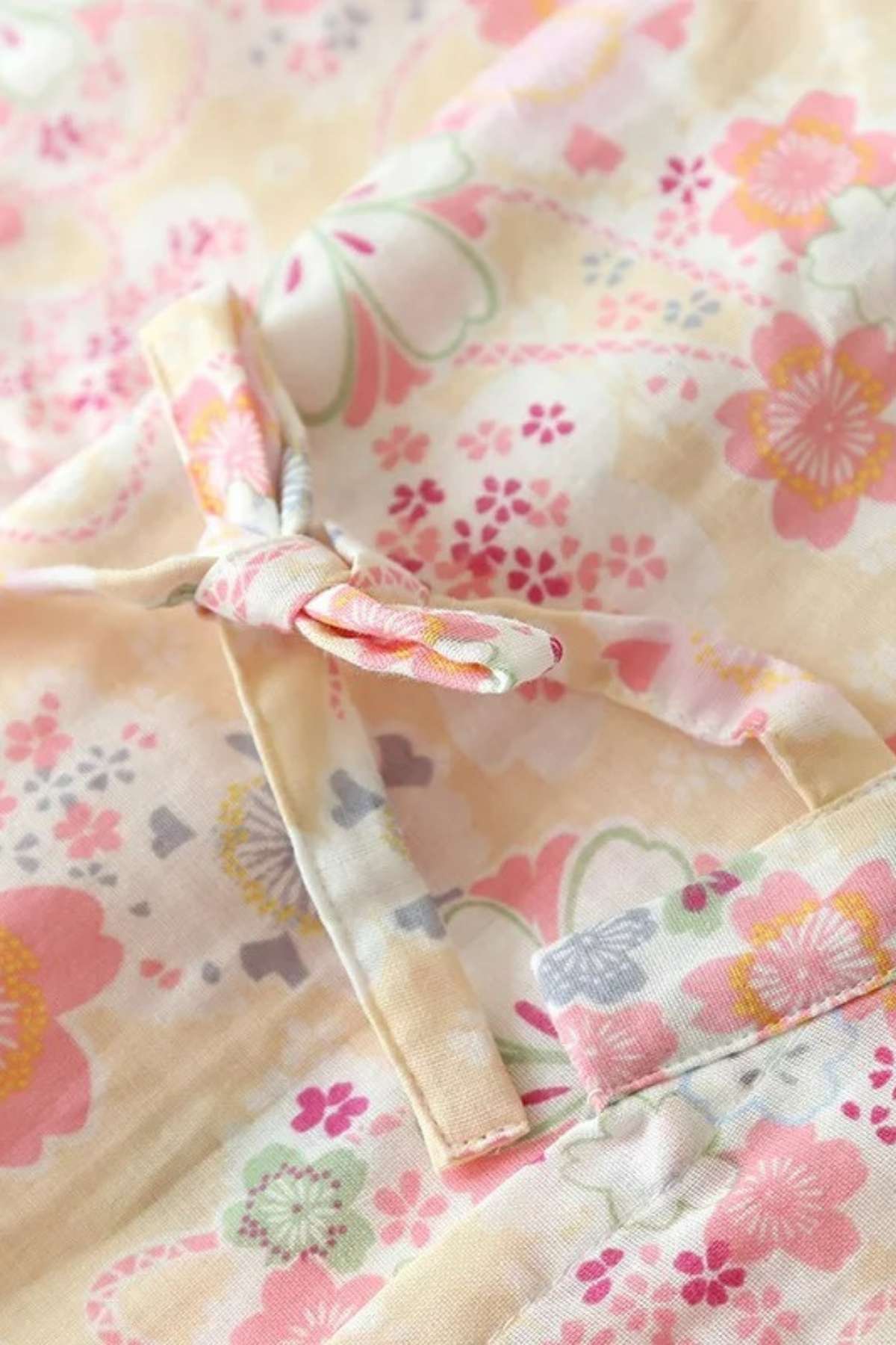 Tissu de kimono avec motifs floraux colorés dans des tons de rose, jaune et vert, noué délicatement