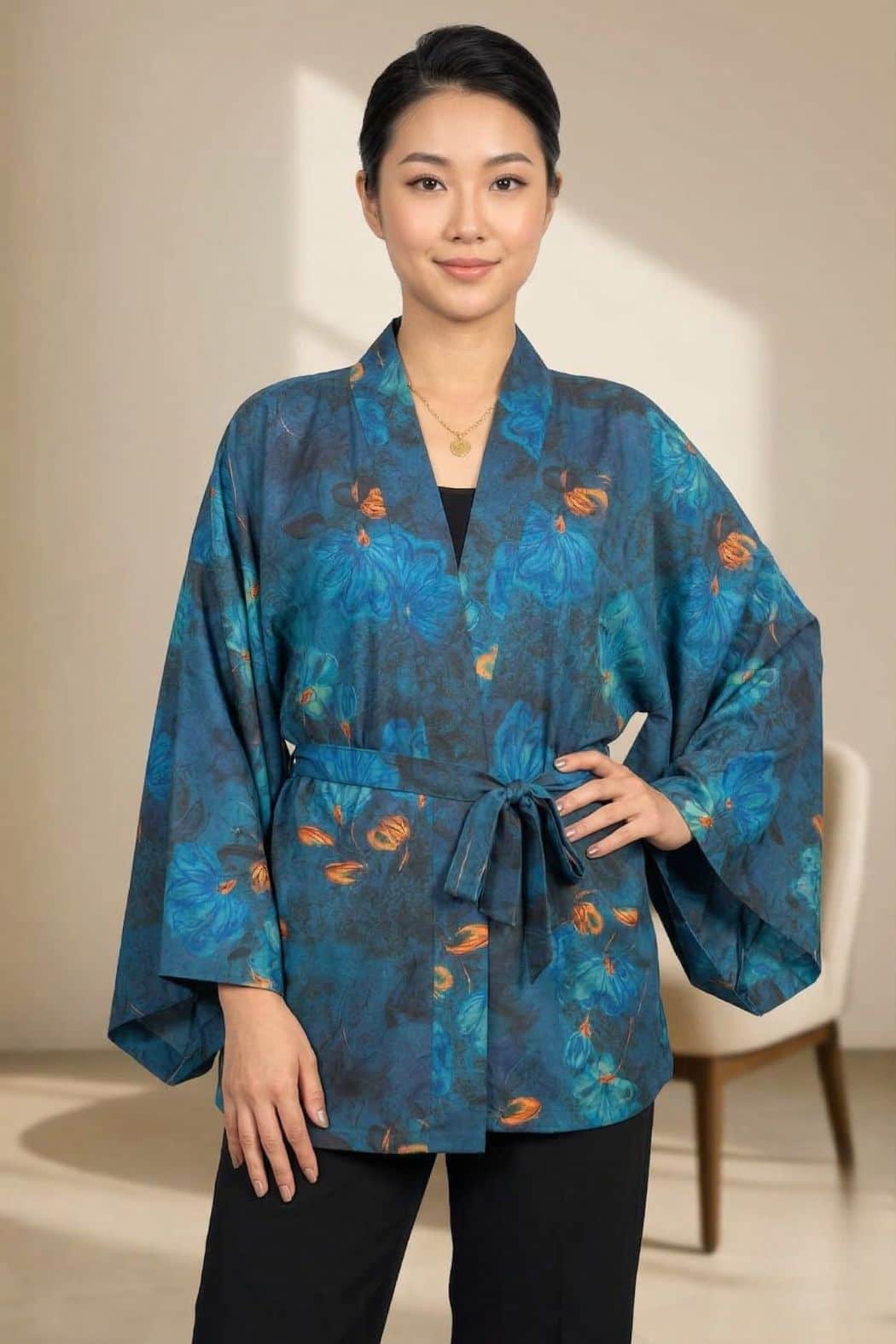 Veste kimono femme en tissu bleu avec motifs floraux, portée avec un pantalon noir dans un décor moderne