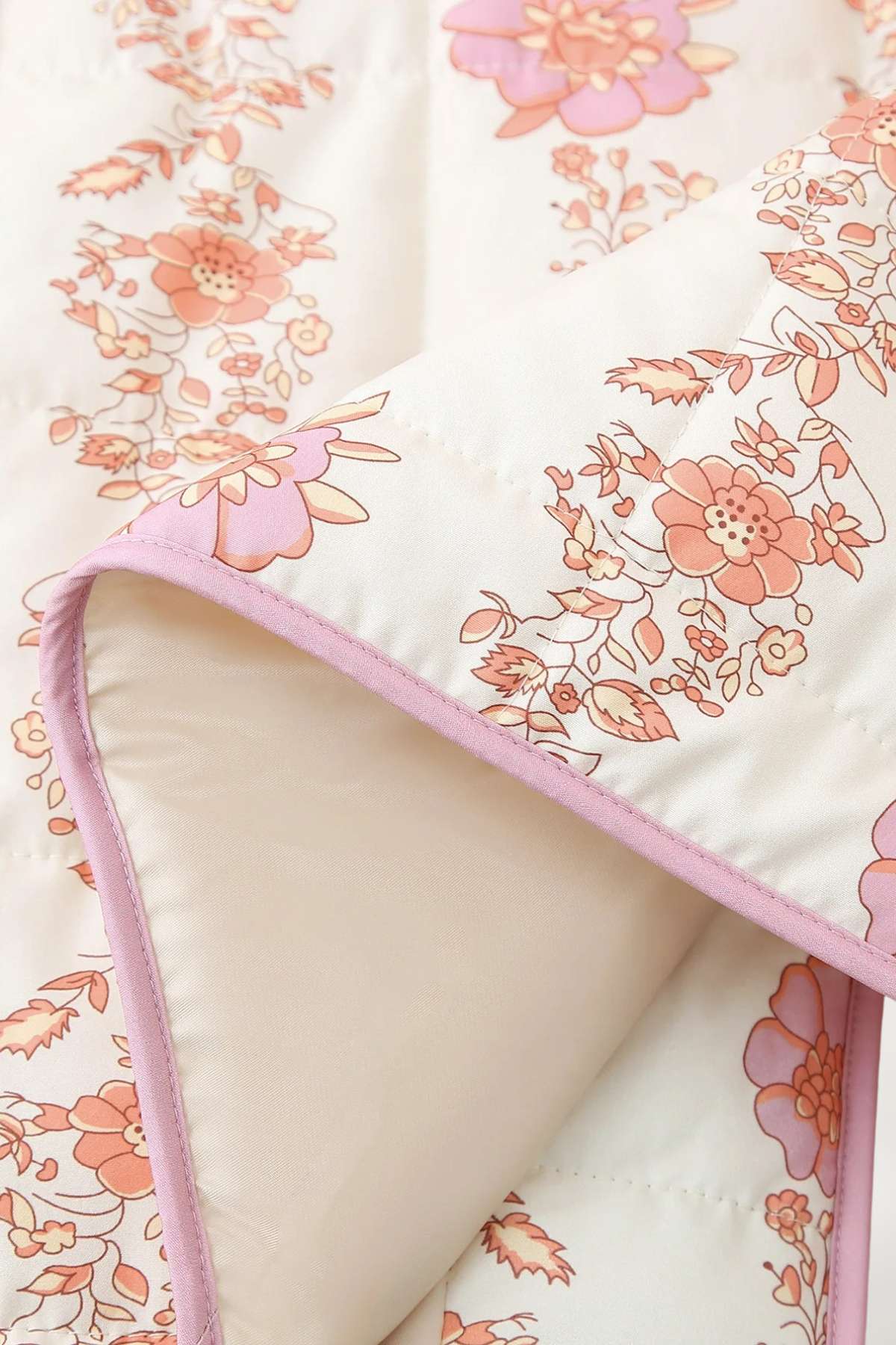 Gros plan sur le tissu matelassé et les motifs de pivoines roses de la veste kimono plissé Kimoky