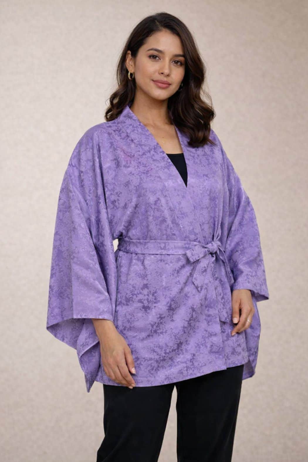 Veste kimono femme en tissu violet avec motifs floraux subtils, portée avec un pantalon noir, fond neutre
