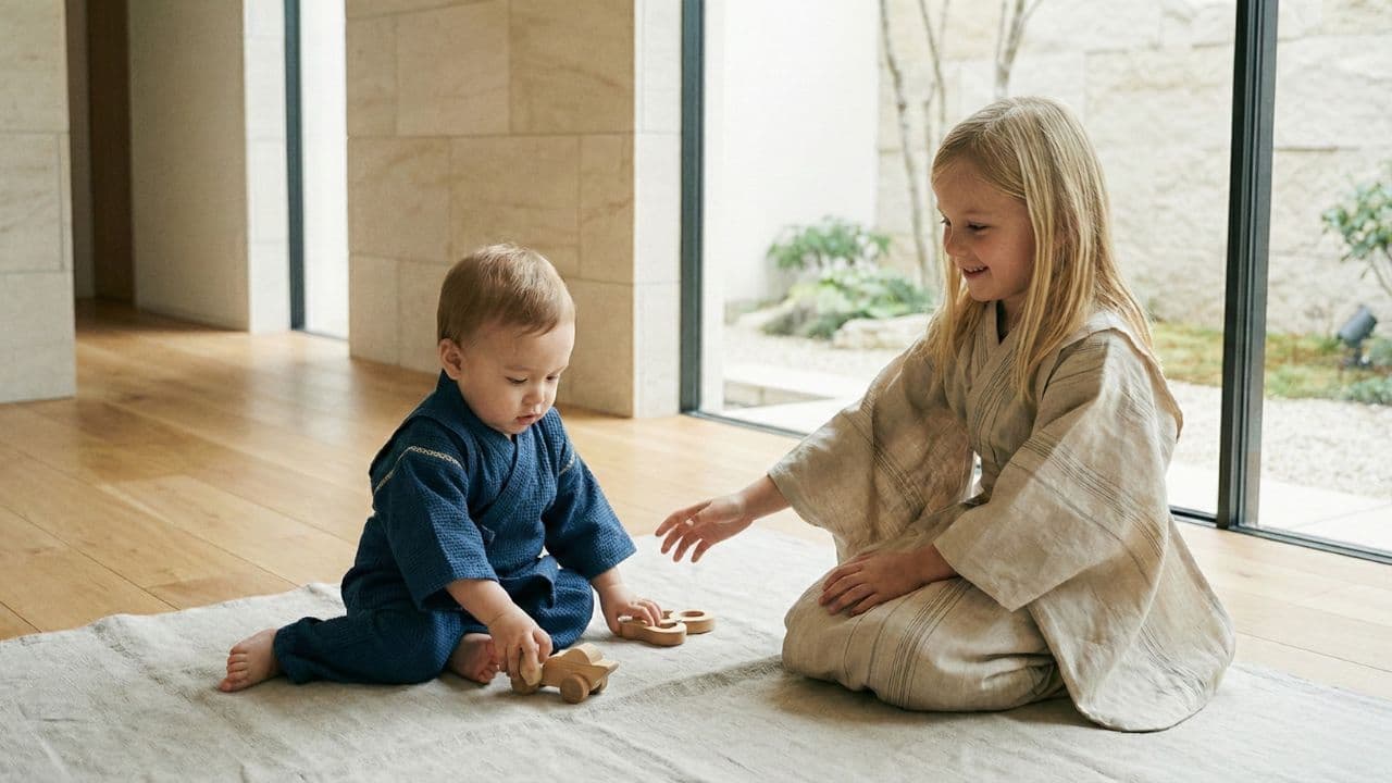 Bébé et enfant portant des kimonos Kimoky, assis sur un tapis en intérieur lumineux, illustrant la collection kimono enfant inspirée du style japonais