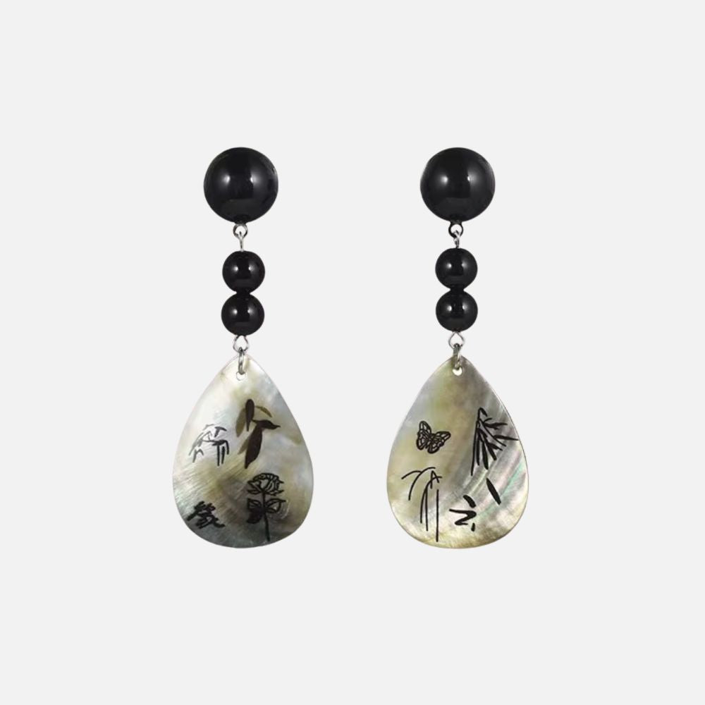 Boucles d'oreilles en nacre avec motifs poétiques, perles noires et forme goutte, évoquant un style japonais élégant.