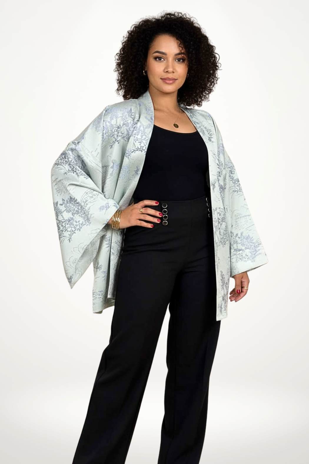 Femme portant un kimono gris clair avec motifs floraux bleus, associé à un pantalon noir, en pose élégante