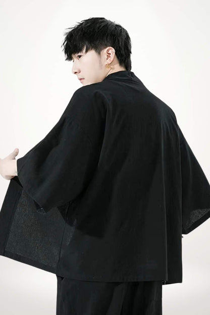 Homme en kimono noir, dos tourné, avec une coupe de cheveux moderne sur fond blanc minimaliste