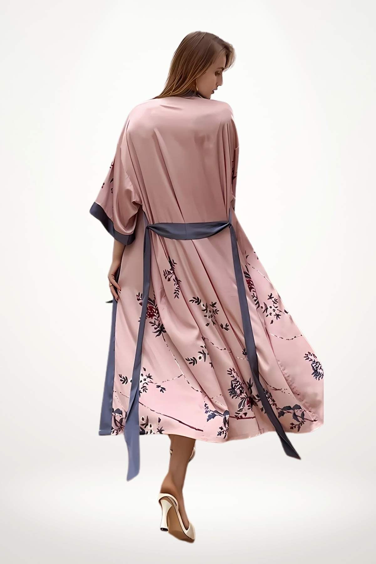 Kimono en satin rose avec motifs floraux, ceinture bleu foncé, femme en posture élégante sur fond clair