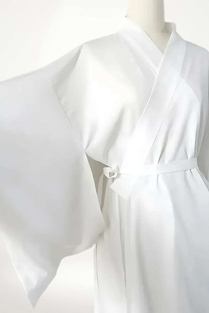 Kimono blanc en tissu léger, avec des manches larges et une ceinture nouée, évoquant la tradition et la pureté