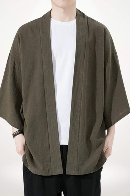 Homme portant un kimono moderne de couleur olive, avec un t-shirt blanc et un fond neutre