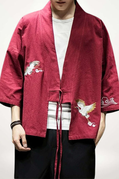Un homme porte un kimono rouge avec des motifs de phénix brodés, associé à un t-shirt blanc et un pantalon