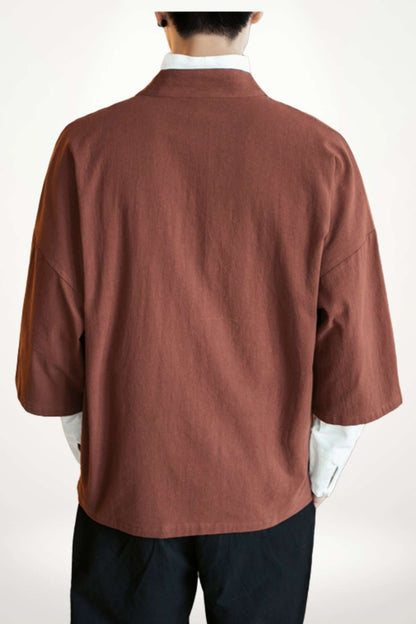 Homme de dos portant un kimono en lin marron, avec des manches larges et un col blanc, sur fond neutre