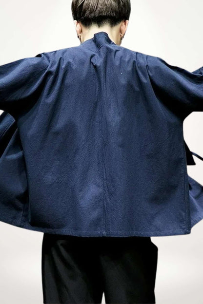 Homme portant un kimono japonais bleu marine, aux manches larges, dans un décor minimaliste et lumineux