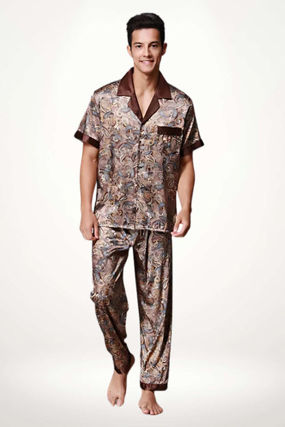 Homme souriant portant un pyjama en satin aux motifs marron et doré, avec un col noir, sur fond clair