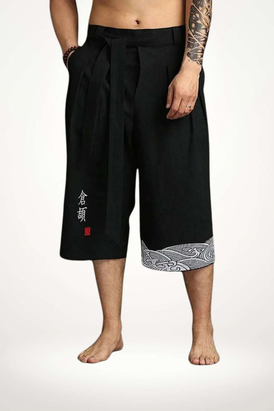 Pantalon kimono noir en tissu léger avec un motif blanc sur le bas, porté par un homme pieds nus