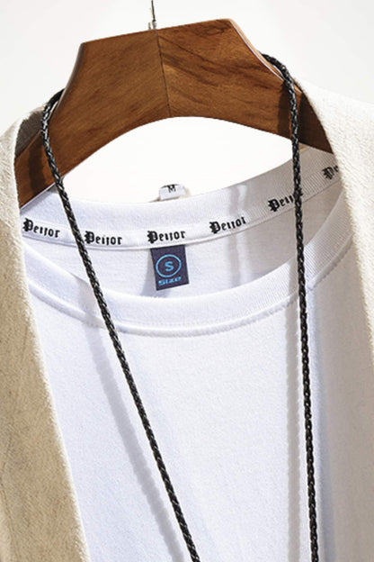 Un t-shirt blanc suspendu sur un cintre en bois, avec un léger motif noir sur le col