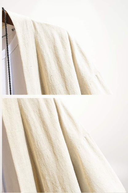 Un kimono en tissu beige clair, avec une texture douce et légèrement froissée, suspendu sur un cintre