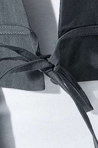 Détail d'un kimono pour homme en tissu gris, avec un nœud élégant et un fond blanc texturé