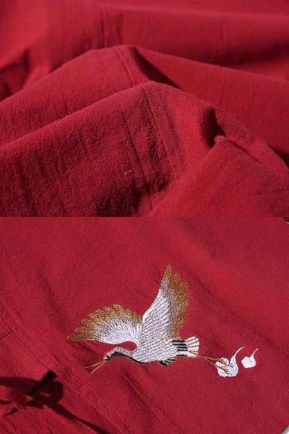 Tissu rouge avec des plis, décoré d'une broderie représentant une grue en vol et des fleurs