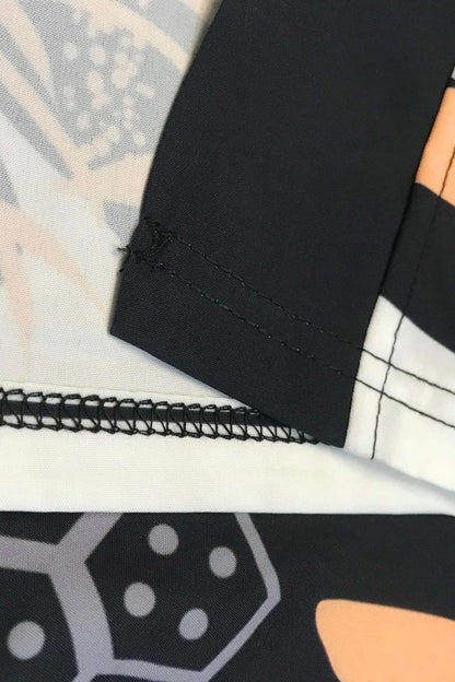 Détail d'une chemise kimono avec motifs géométriques noirs et orange, couture noire sur tissu léger