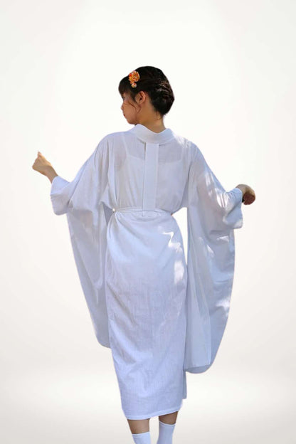 Femme de dos portant un kimono blanc, aux manches larges, dans un décor minimaliste et lumineux