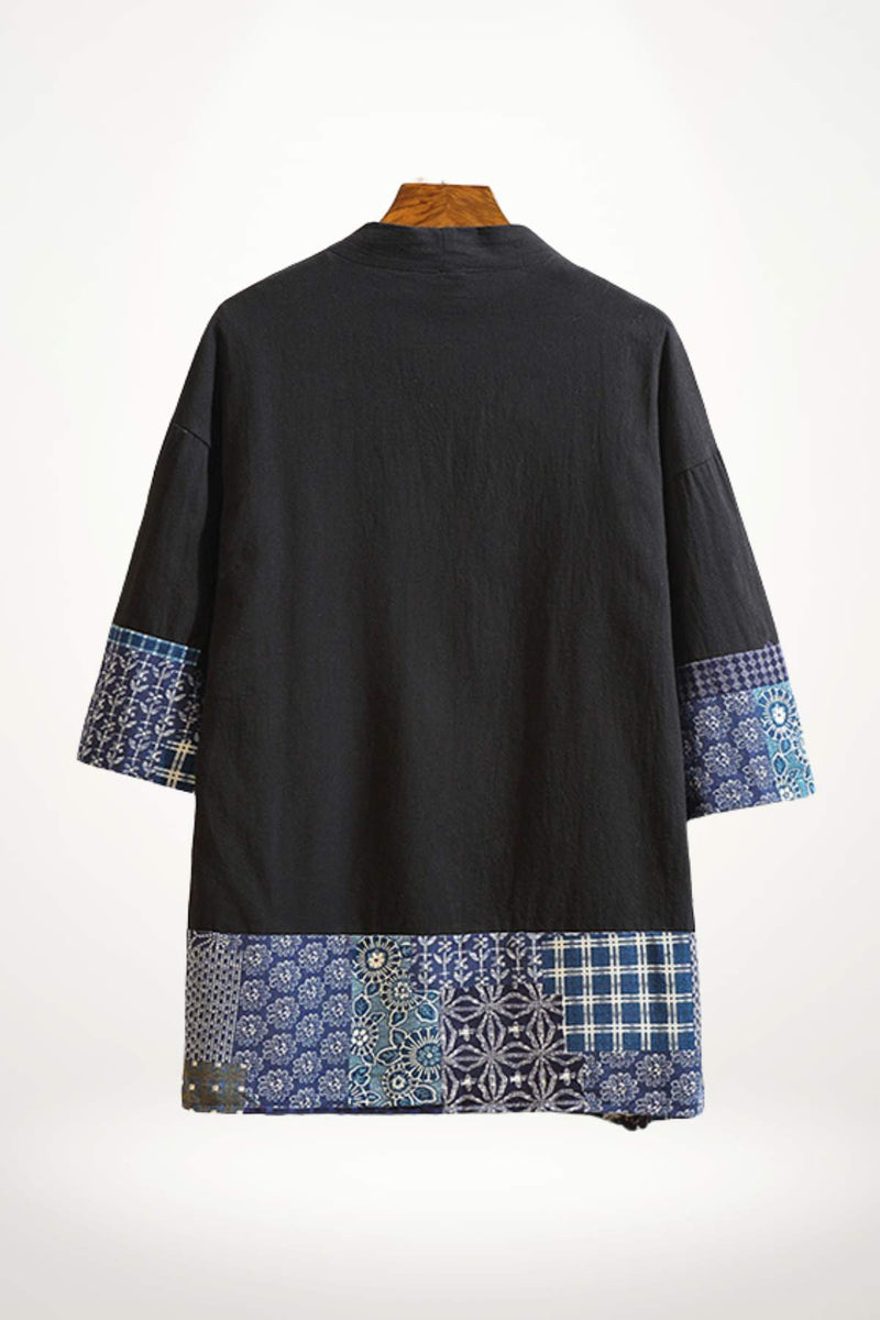 Veste noire au style kimono avec manches larges et motifs bleus sur les bords, fond uni et élégant