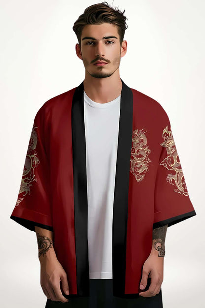 Un homme porte un blazer kimono rouge avec des motifs dorés, sur fond clair, dégageant un style minimaliste