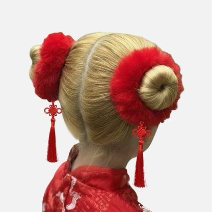 Coiffure traditionnelle avec des chignons blonds ornés de pompons rouges et de pendentifs en soie