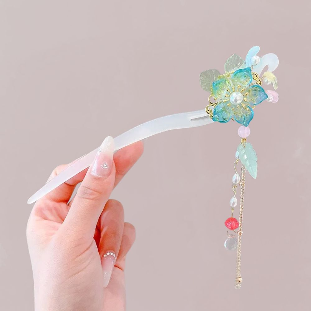 Ornement de cheveux en forme de fleur iridescente avec perles pastel, tenu par une main délicate
